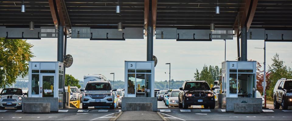 Several cars stopped at a US/Canada border crossing.