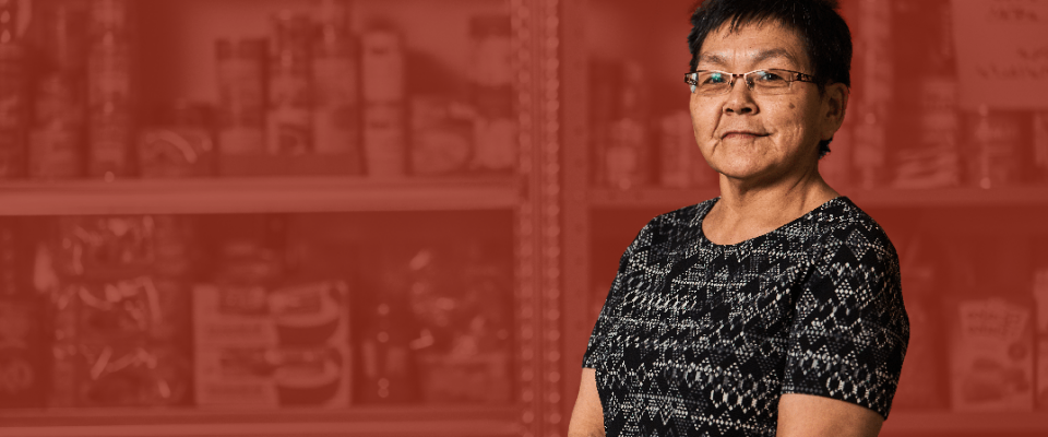 Indigenous woman standing in from of shelves in a red backgrounds