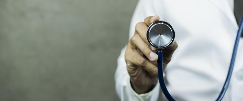 Person in white lab coat holding stethescope