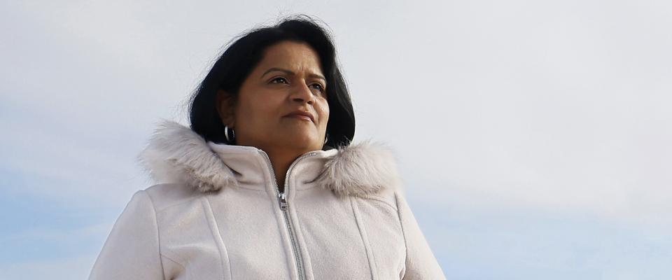 Photo of Sharon DeSousa in a white coat with the sky in the background