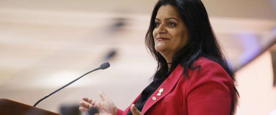 Sharon DeSousa sourit et parle à un microphone. 