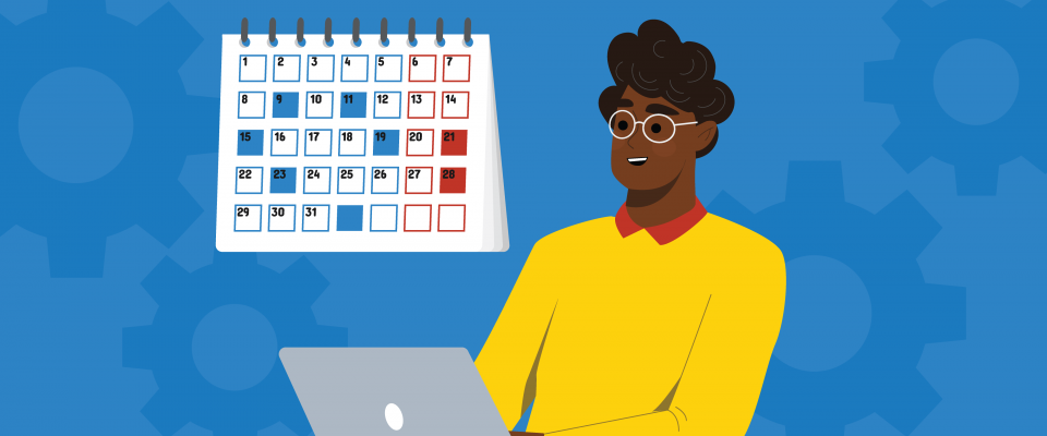 A person working on a laptop in front of a calendar