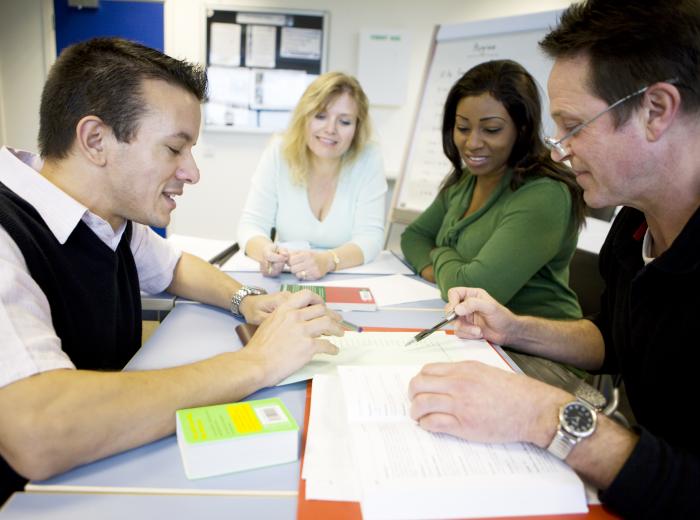 four workers in an office looking at documents