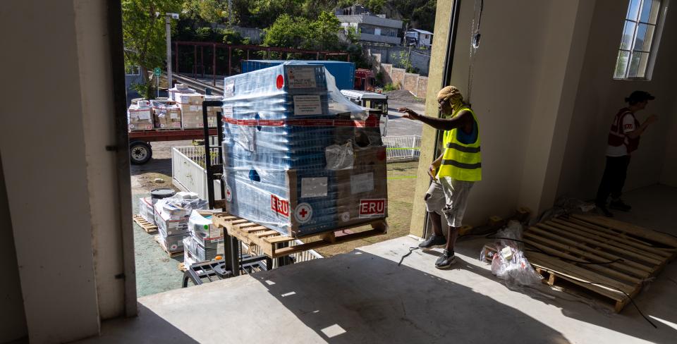 A photo showcasng aid items being placed in storage by aid workers
