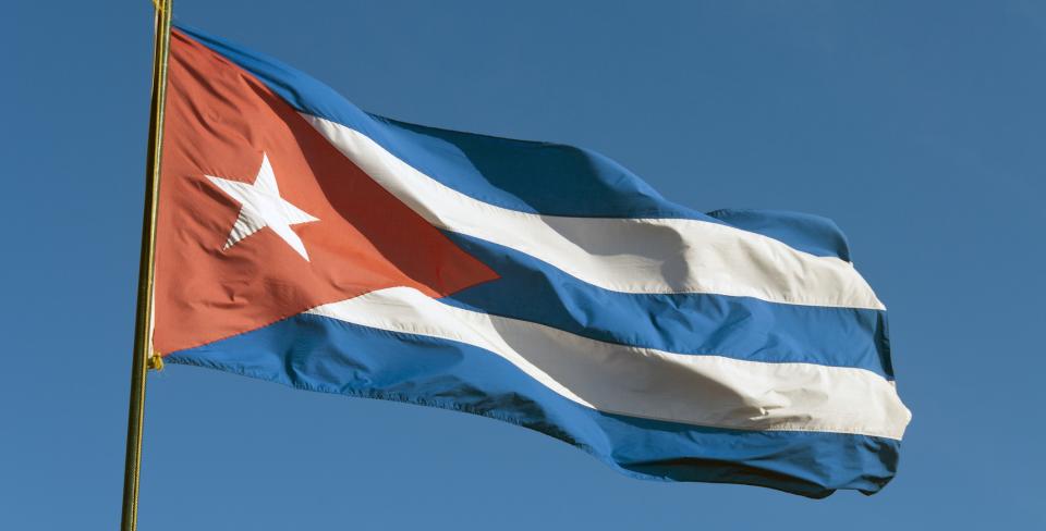The Cuban flag waving against a clear blue sky.