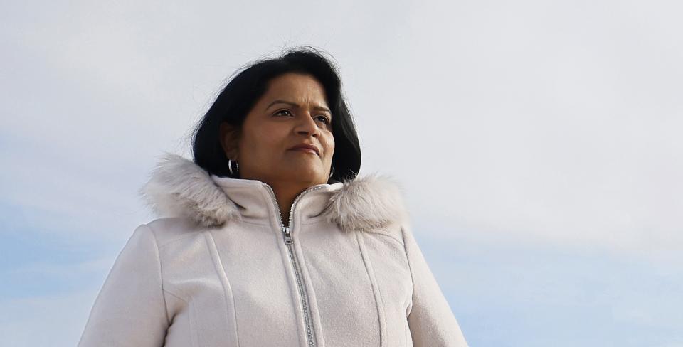 Photo of Sharon DeSousa in a white coat with the sky in the background